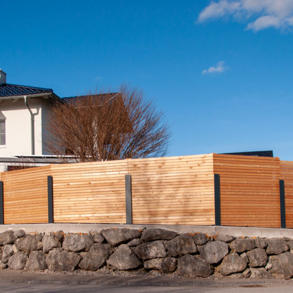Sichtschutzzaun aus Holzlatten mit Metallpfosten auf einer Natursteinmauer