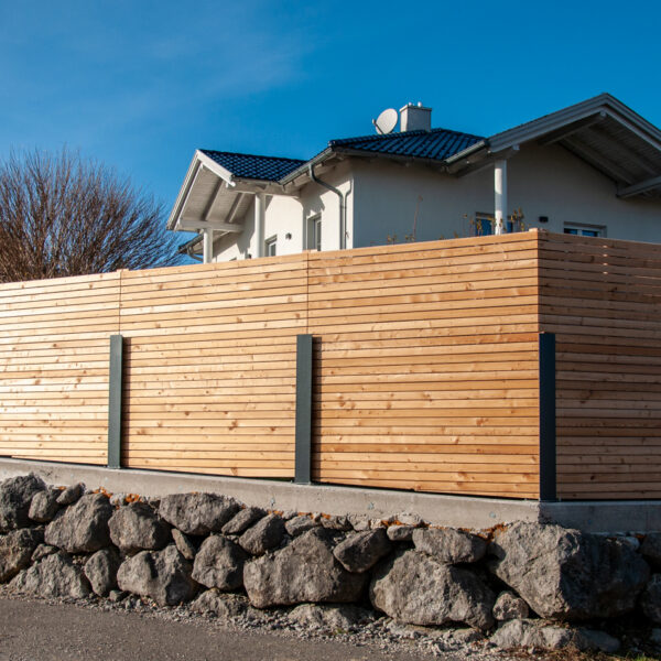 Ecklösung eines Sichtschutzzauns aus Holz mit Metallstehern vor einem Wohnhaus