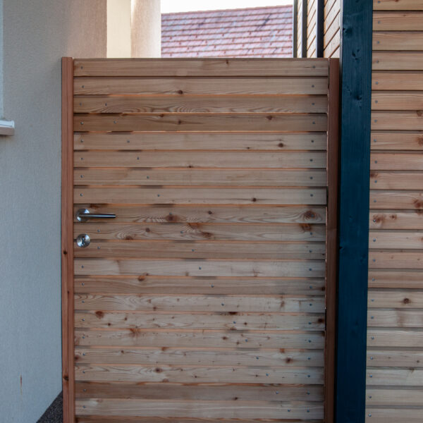 Kleine Holztüre mit Edelstahlgriff, eingebaut in Holzverkleidung